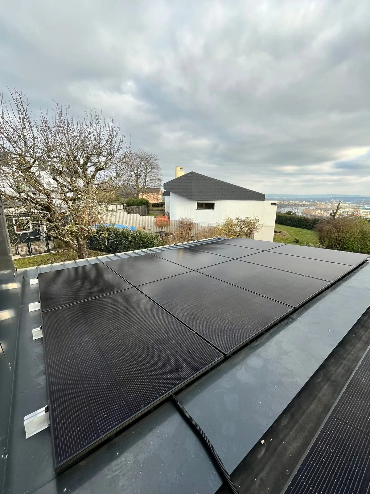Solarmodule auf einem Flachdach in Neuwied, im Hintergrund das Rheintal