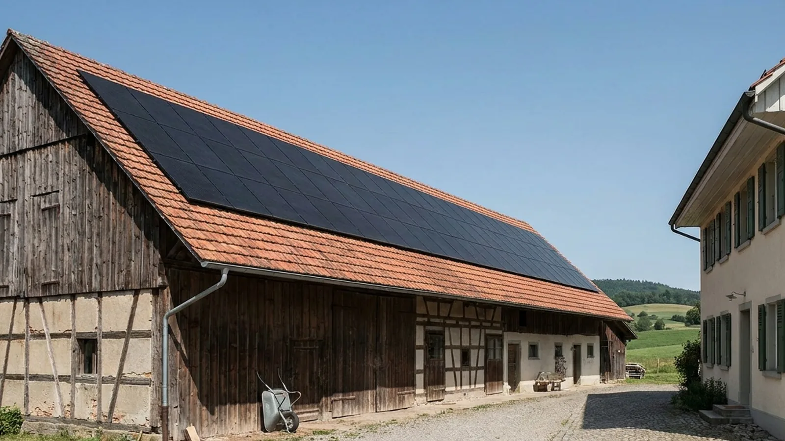 Scheune mit großem Modulfeld auf dem Dach, daneben das Wohnhaus am Hof